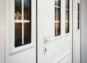 Up-close picture of white door with a lever knob to the front entrance of a home. 
