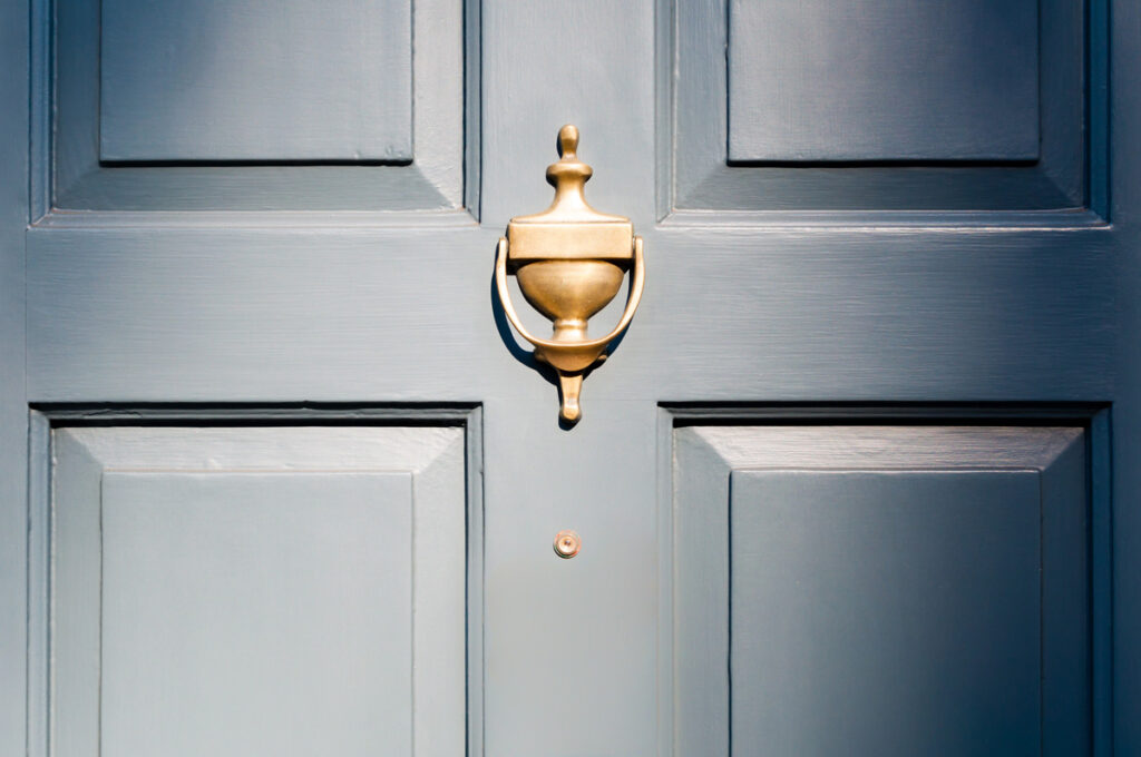 A close-up image of a navy blue new residential door with gold hardware in El Paso.